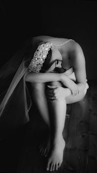 Artistic black and white photo of a bride in contemplation wearing a beaded veil.