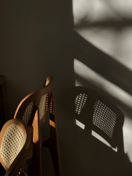 Cane-back chairs casting lattice shadows on a wall — photo by Iryna Korovchenko on Pexels
