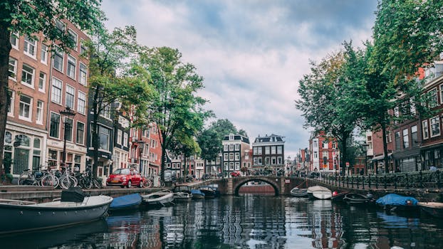 Charming view of an Amsterdam canal lined with bicycles, boats, and historic buildings. by Chait Goli