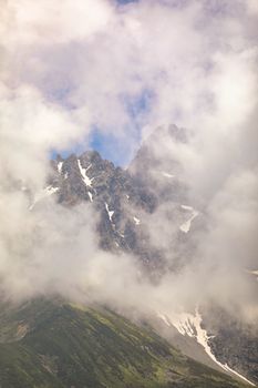 Snowcapped mountain peaks shrouded in fog and clouds create a dramatic landscape view.