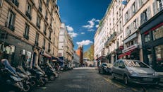 巴黎街景如画，以经典建筑、停放的摩托车和汽车为特色