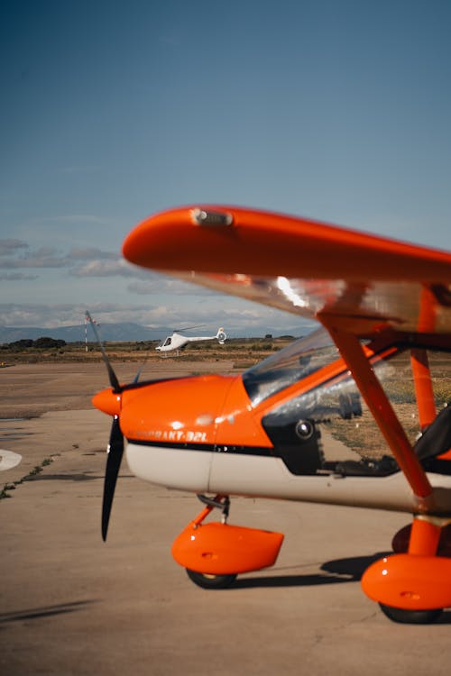 A small orange airplane sitting on the tarmac