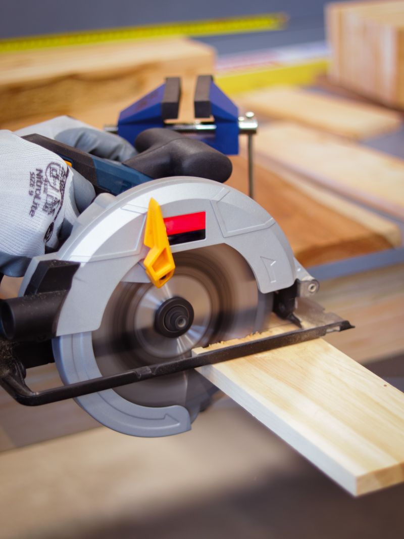Close-up of carpenter using a circular saw on a plank indoors with selective focus.