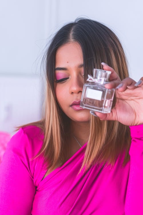 A woman in pink holding a perfume bottle