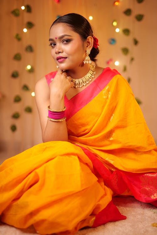 A beautiful woman in a yellow sari sitting on the floor