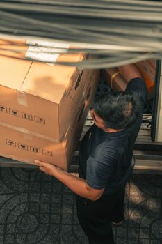 Delivery worker loading boxes from truck on urban city street during daytime.