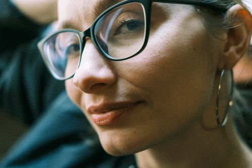 Free Close-up portrait of a woman wearing eyeglasses and hoop earrings, exuding confidence and style. Stock Photo