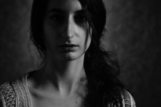 Moody black and white portrait of a woman, highlighting shadows and texture.