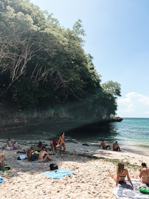 People are relaxing on the beach near a cliff