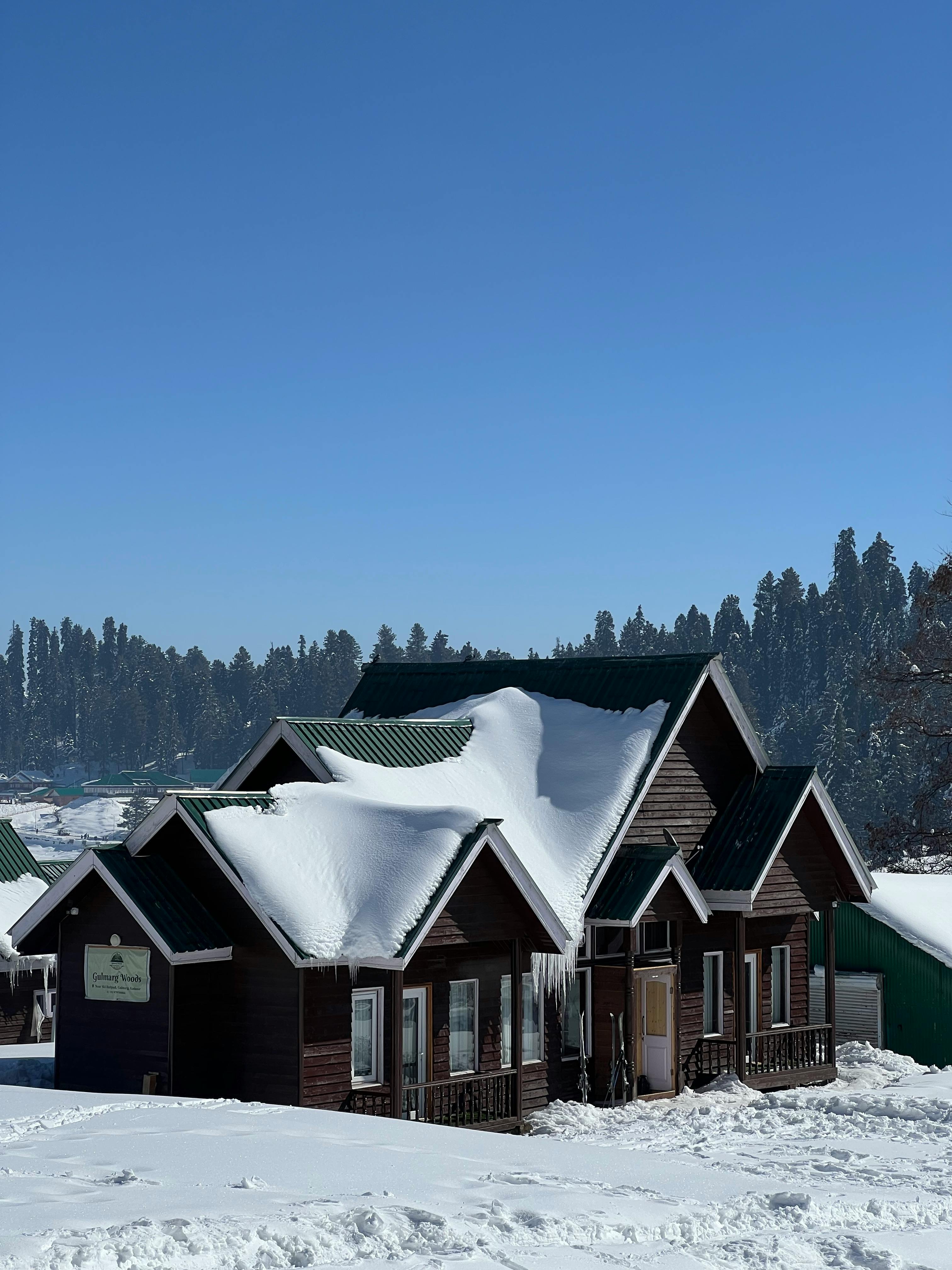 Prescription Goggle Inserts - Wooden houses blanketed in snow under a clear blue sky in Gulmarg during winter.