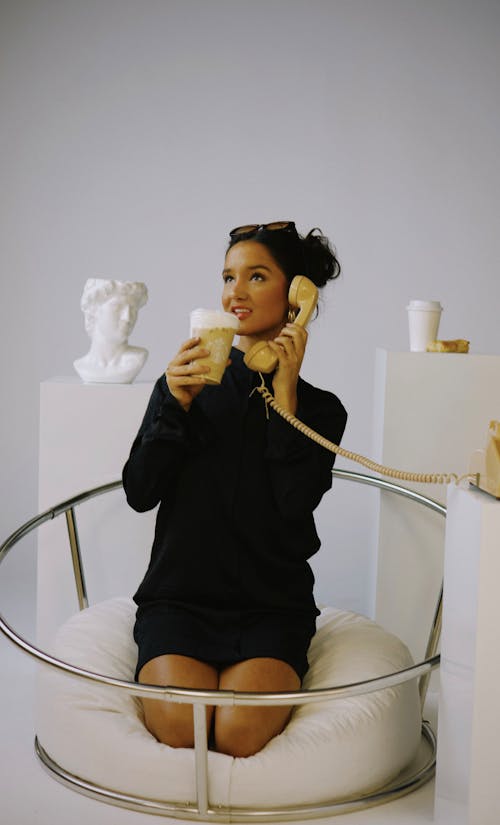 Brunette Woman Kneeling with Telephone Handset and Cup of Coffee