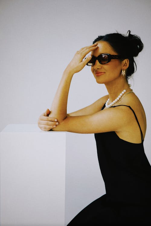 A woman in a black dress and sunglasses posing for a photo