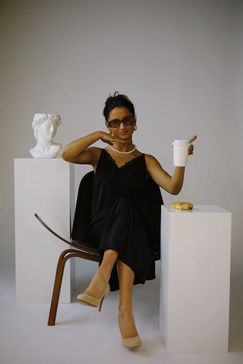 Woman Posing with a White Cup next to the David Bust