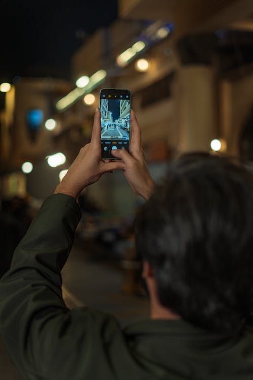 Man Taking Pictures with Smartphone at Night