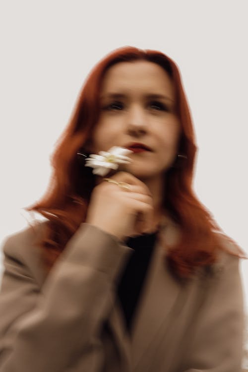 A woman with red hair holding a flower