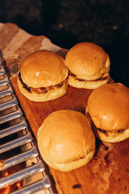 Three sliders on a grill with a wooden board