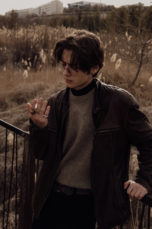 A man in a leather jacket and glasses smoking