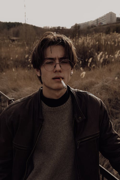 A young man with glasses and a cigarette