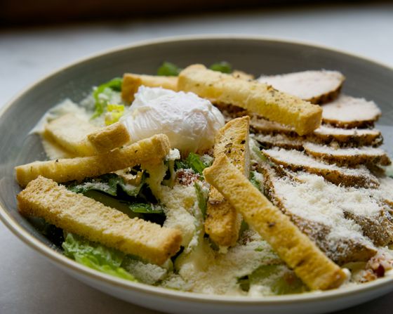 Caesar salad with sliced roast chicken, poached egg, long croutons and grated parmesan