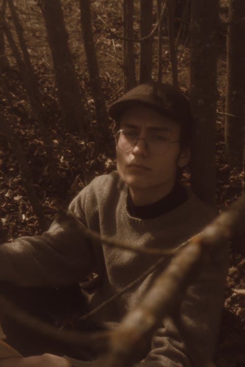 A man sitting in the woods with a hat on