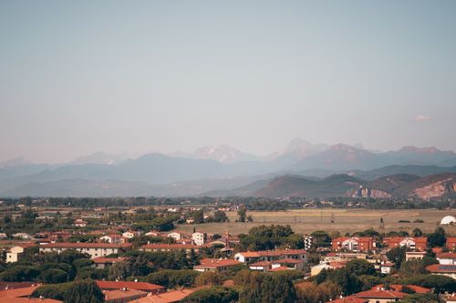 Free Aerial view of Pisa, Italy, highlighting the Apuan Alps in the background during a warm summer day. Stock Photo