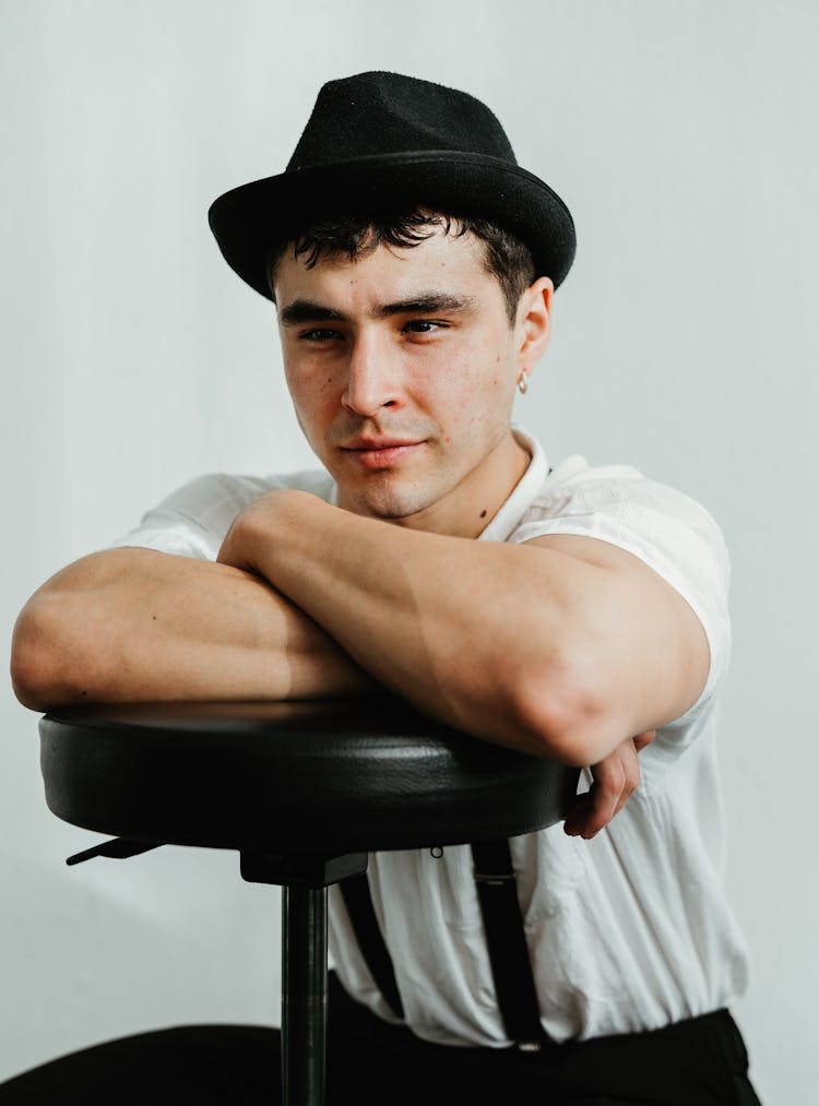 Young Man In Hat Sitting On Chair