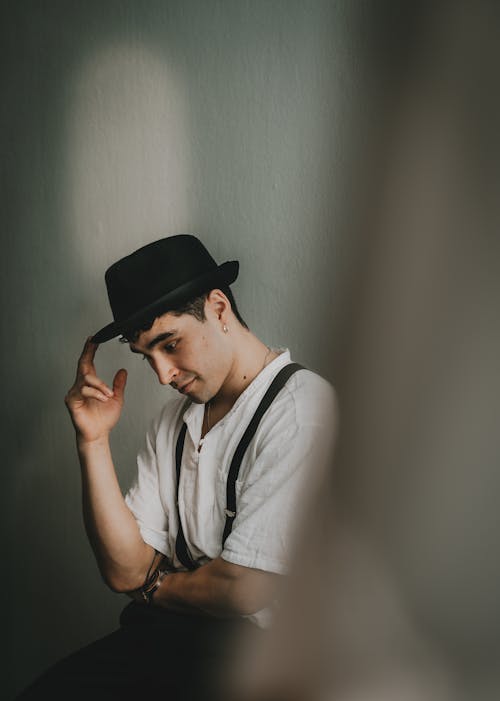 Man in Suspenders Fixing Hat