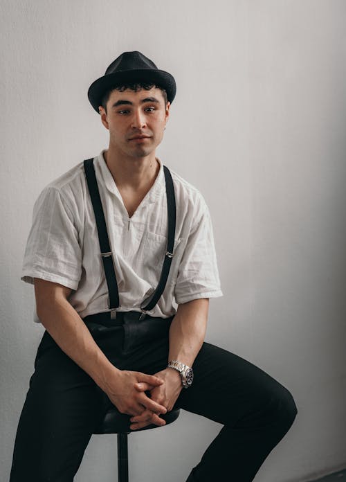 Man in Hat and White Shirt Sitting on Chair