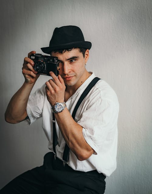 Man in Shirt and Hat Sitting with Camera