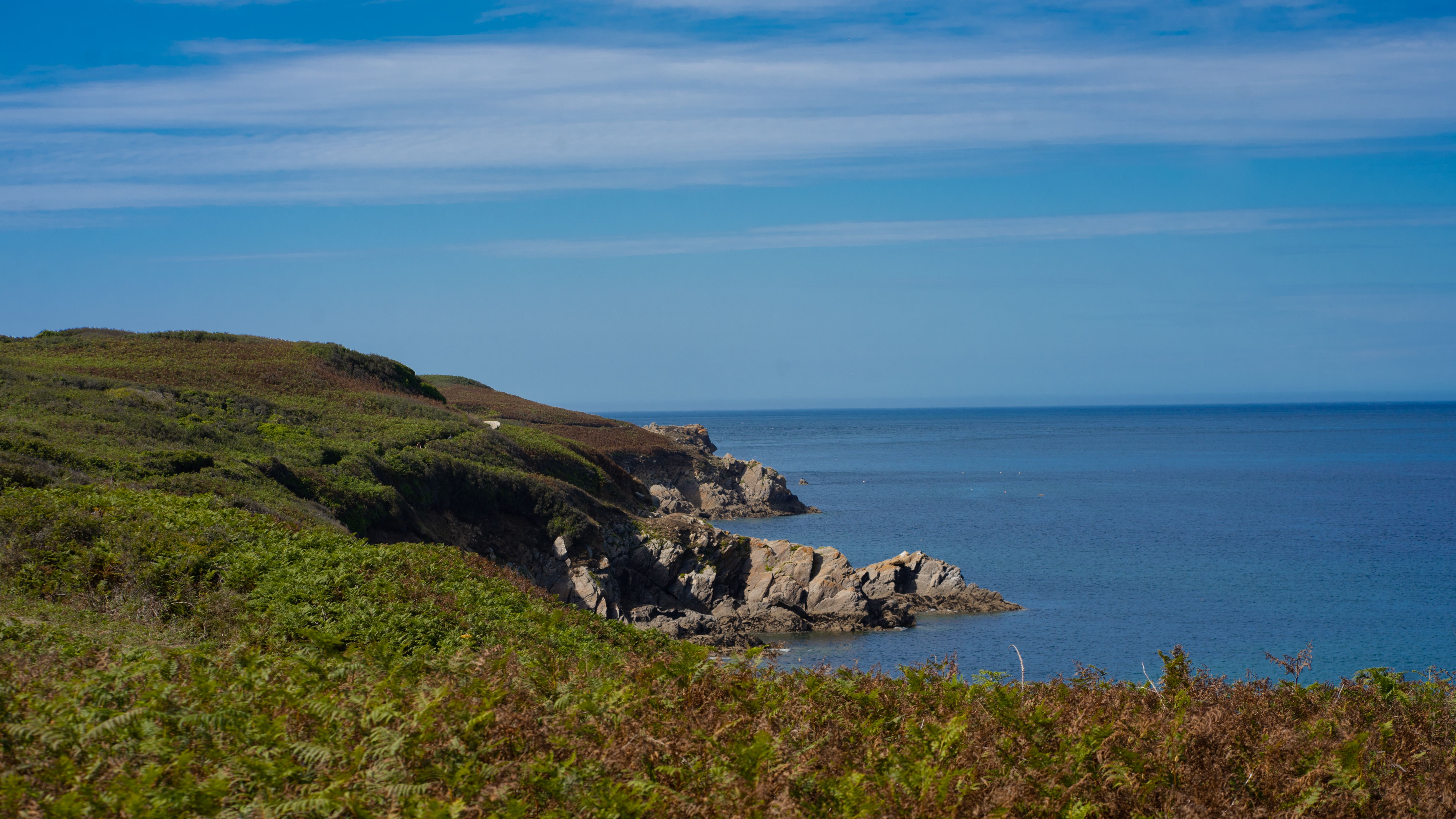 Breathtaking view of rocky cliffs along a serene ocean coastline under a clear blue sky.