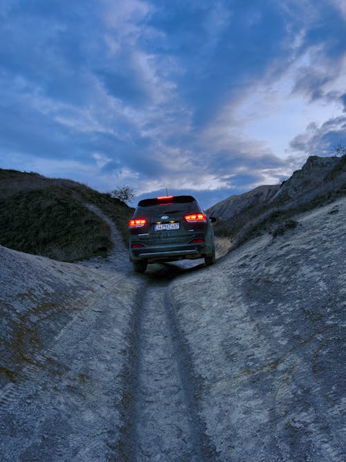 Kia Car on Dirt Road among Hills