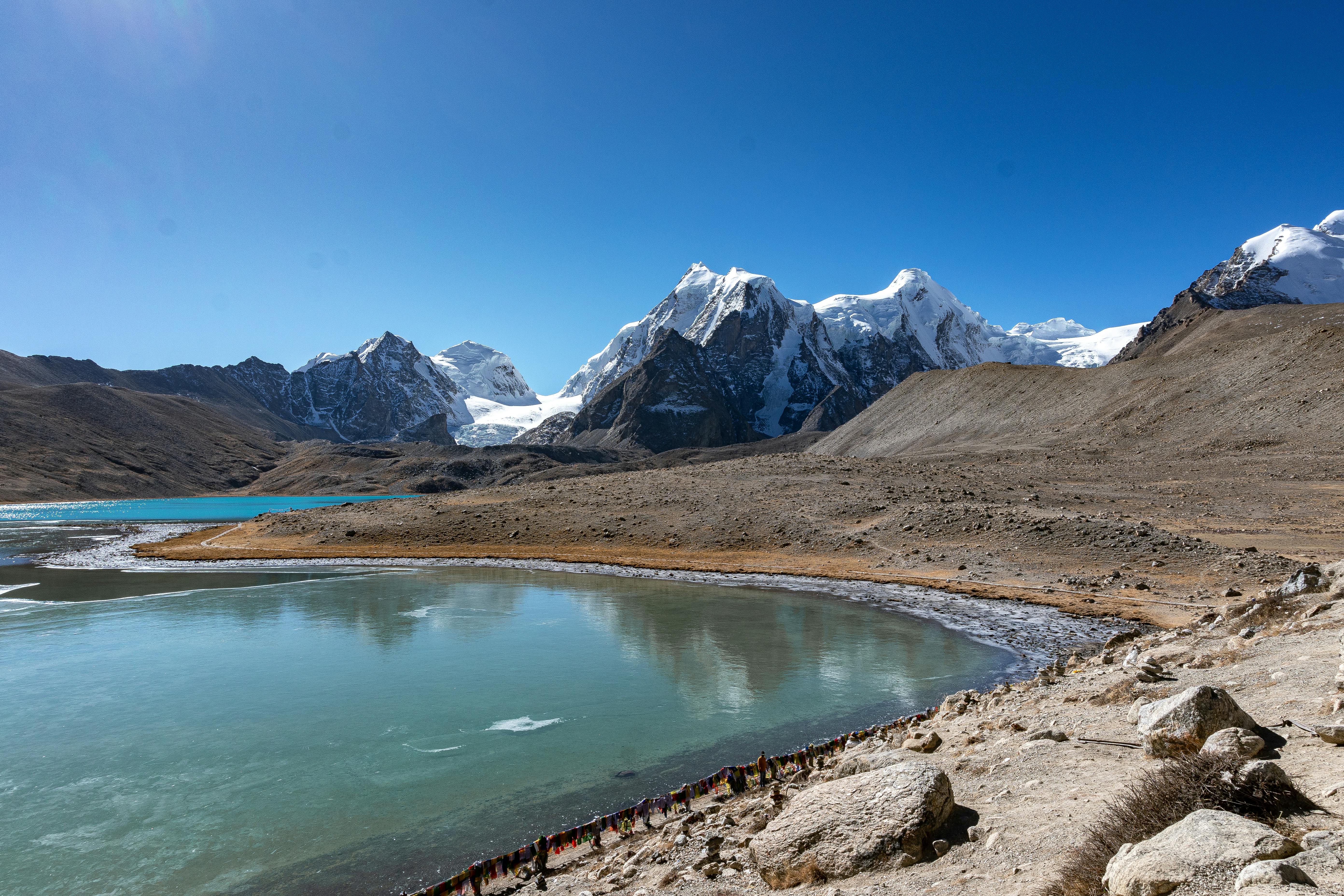 Experience the breathtaking landscape of Yumthang, SK, India with snowcapped peaks and clear reflections.