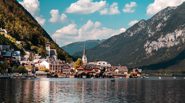 Explore the picturesque town of Hallstatt nestled by a tranquil lake, surrounded by vibrant summer landscapes and majestic mountains.