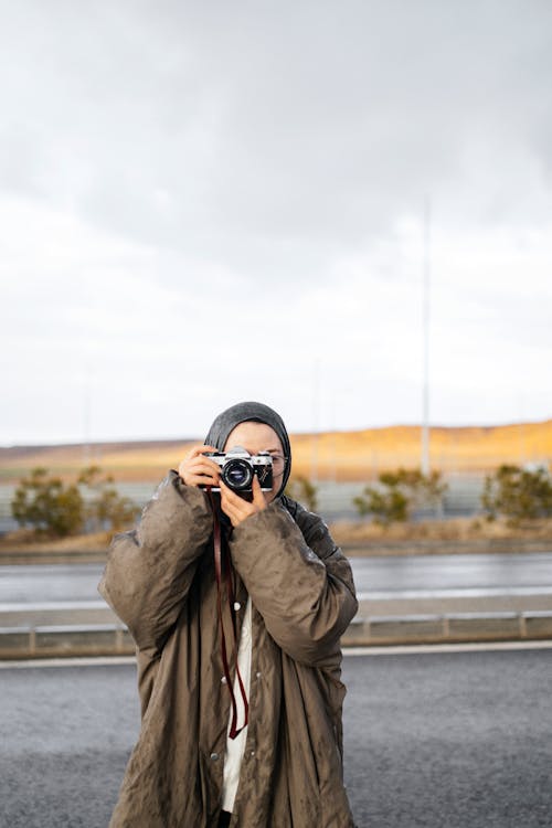 A woman taking a photo with her camera on the road