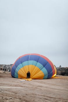 Colorful hot air balloon preparing for flight in a rural landscape at dawn.