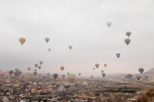 Many hot air balloons flying over a city