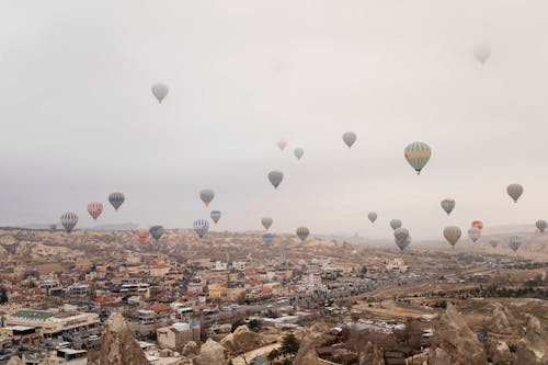 Many hot air balloons flying over a city
