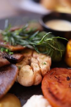 Close-up of grilled mushrooms, tomatoes, and herbs on a plate, highlighting fresh ingredients.