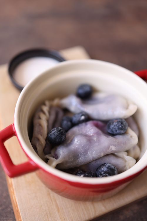 Free Fresh dumplings filled with blueberries served in a red pot, perfect for food photography. Stock Photo