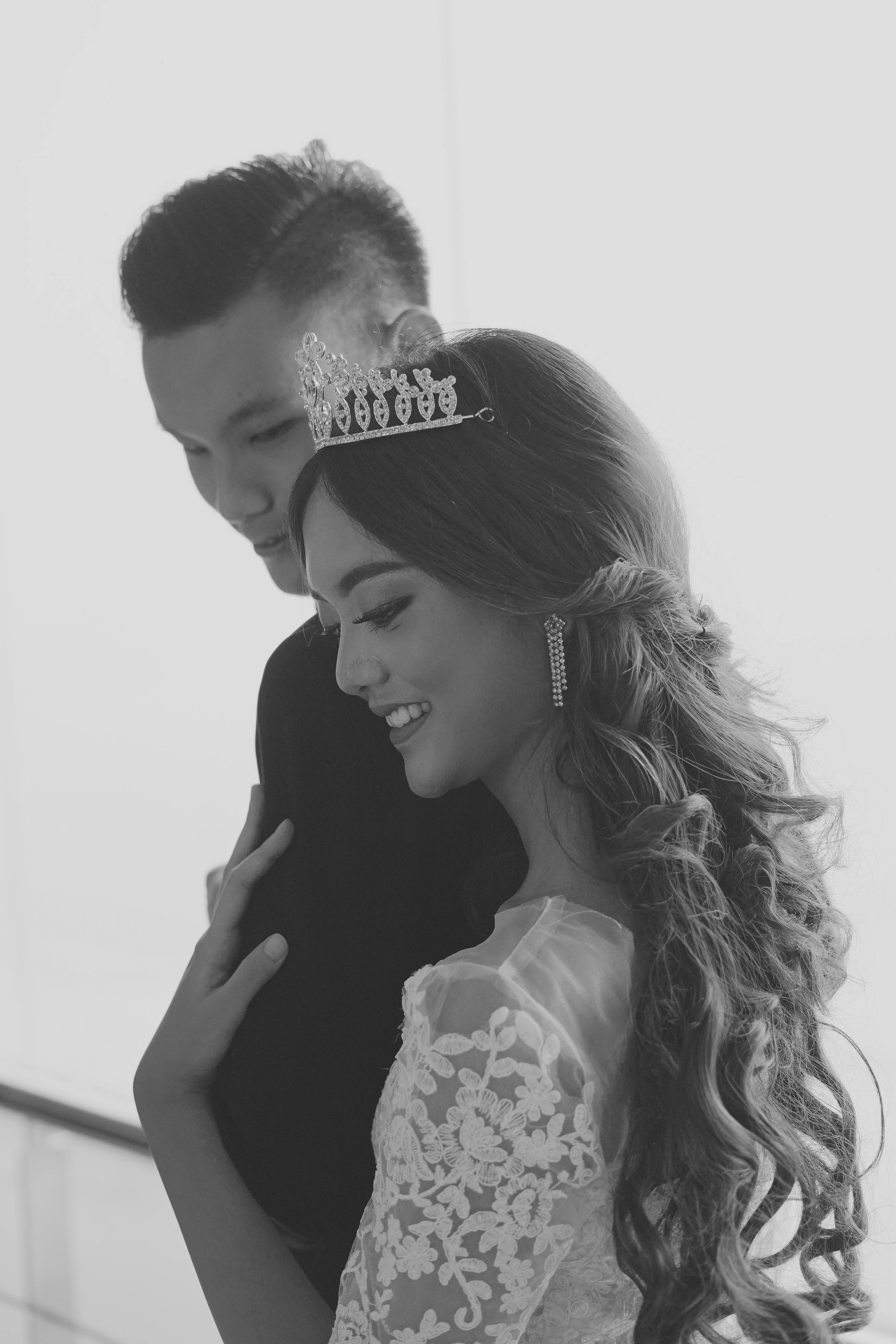 woman wearing tiara leaning on man in black suit