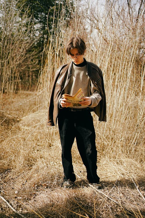 A man standing in a field holding a book