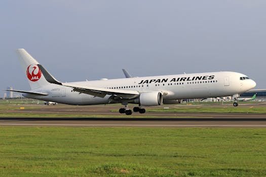 A Japan Airlines airplane landing on a clear day with airport in the background.