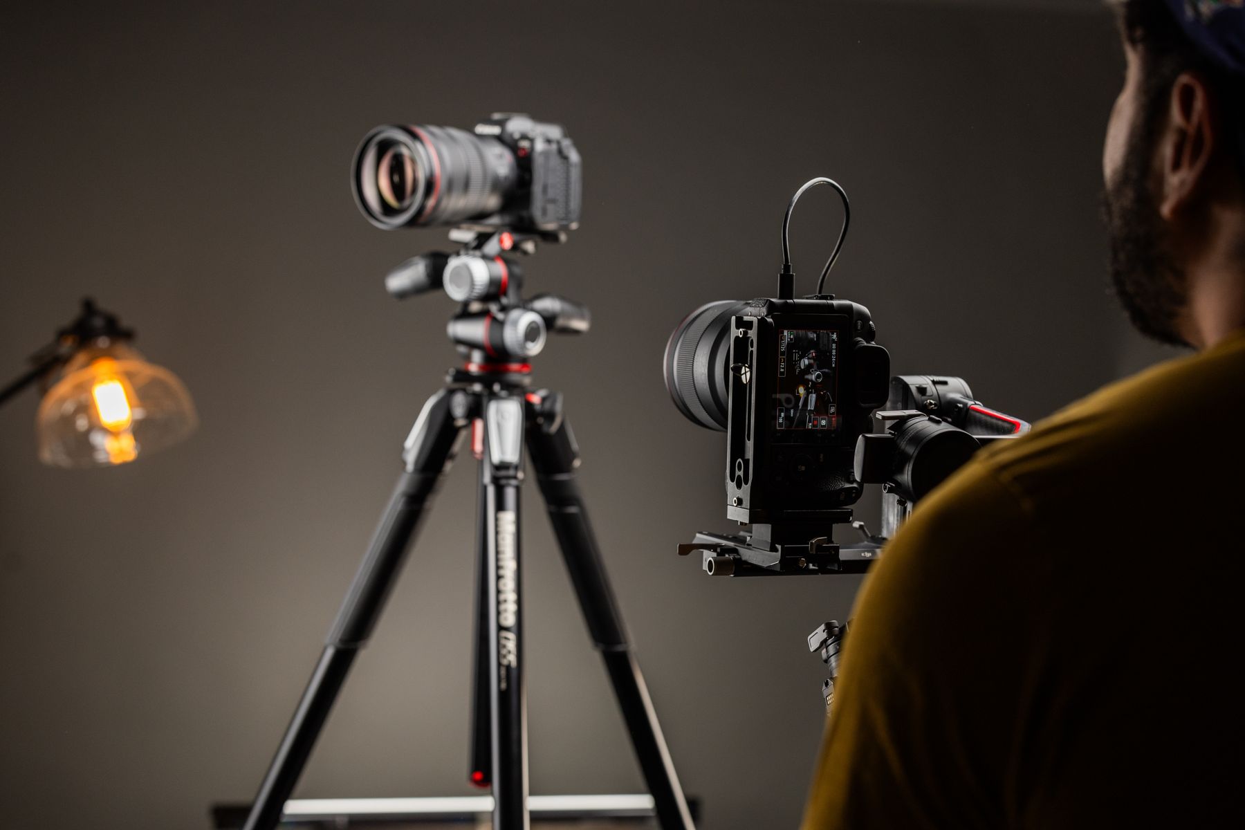 Photographer adjusting a camera on tripod in studio lighting setup
