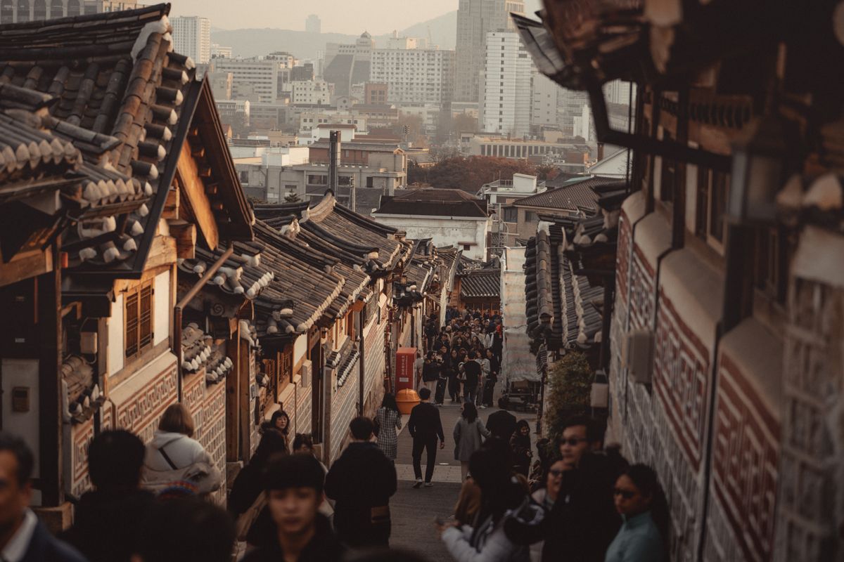 A bustling Bukchon Hanok Village street with traditional Korean architecture.