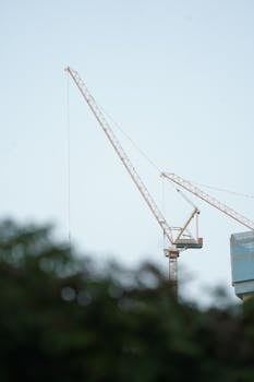 A tower crane against a clear sky at a Jakarta construction site, highlighting urban development.