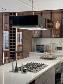Sleek kitchen design featuring a gas cooktop, glass cabinets, and stylish ventilation hood.