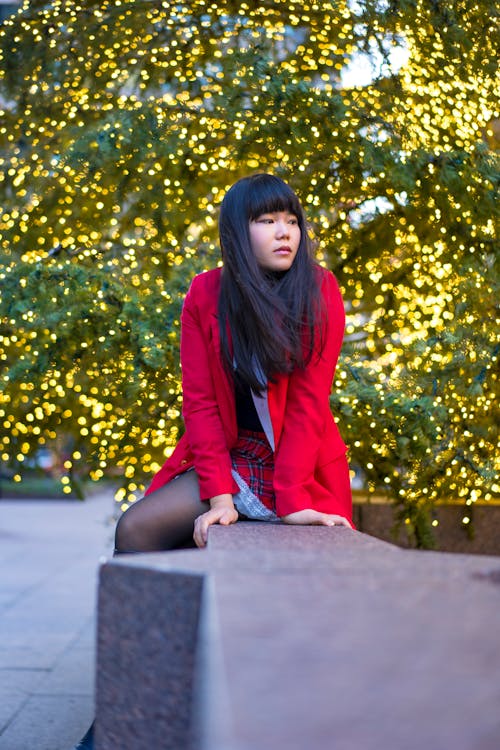 Young Asian Woman Seated Red Jacket Skirt Holiday Lights