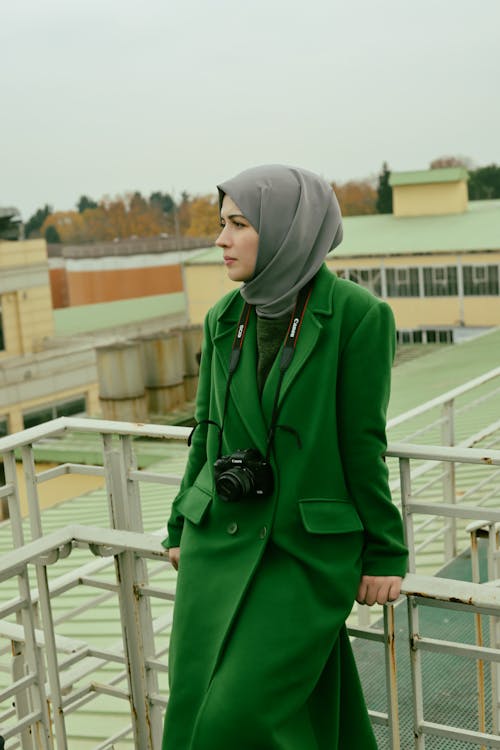 Woman in Hijab and Green Coat Leaning on Railing