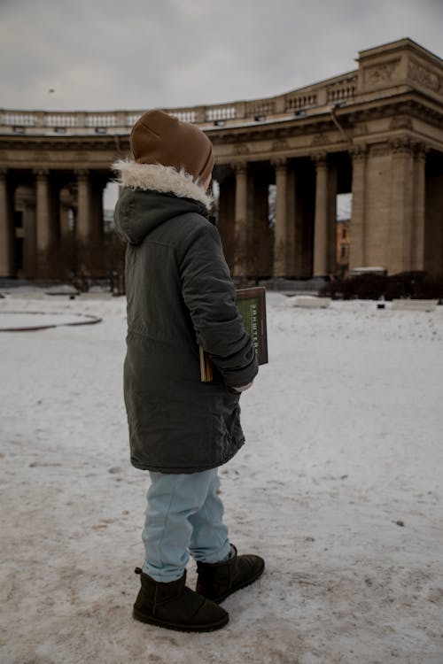 A child standing in front of a building in the snow