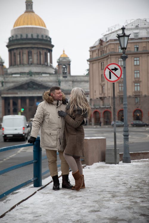 A couple kissing in the snow near a building